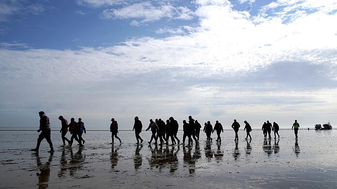 Mutmaßliche Migranten bei Dungeness, nachdem sie nach einem Zwischenfall mit einem kleinen Boot im Ärmelkanal mit einem Rettungsboot der Royal National Lifeboat Institution (RNLI) an Land gebracht wurden.