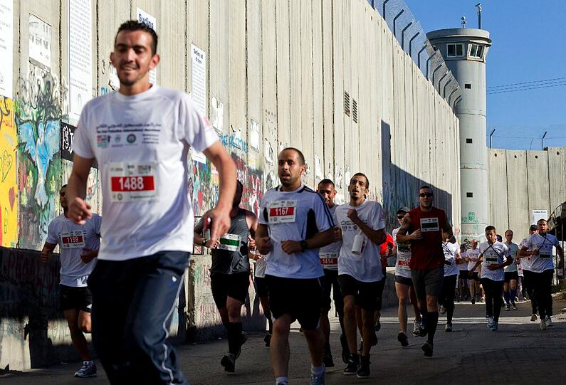 Palästinensische und ausländische Läufer kommen beim zweiten Bethlehem Marathon des Jahres an der israelischen "Sperranlage" in Bethlehem vorbei. Dieses Jahr nehmen rund 3000 Läufer teil, mehr als fünf mal soviele wie im vergangenen Jahr. Der Marathon steht unter dem Motto "Recht auf Freizügigkeit".