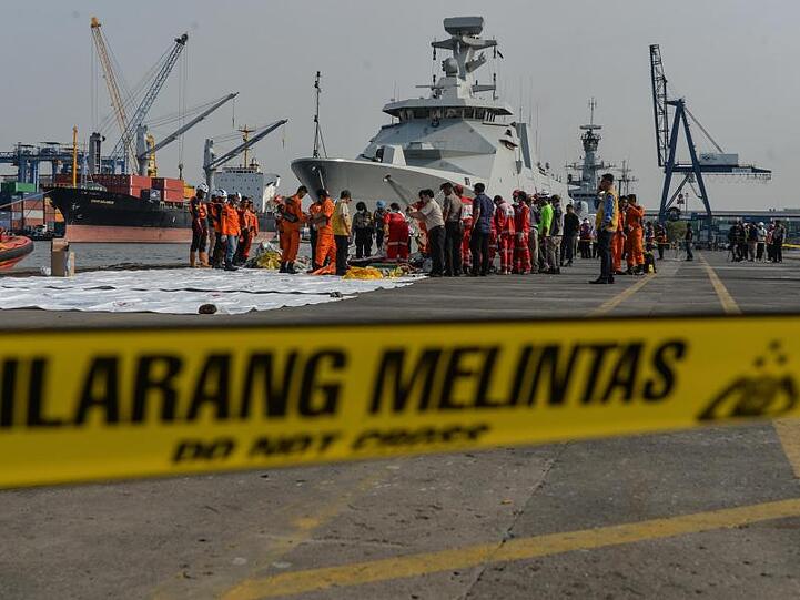 Mitarbeiter der Such- und Rettungsbehörde sortieren Wrackteile der abtestürzten Boeing 737.