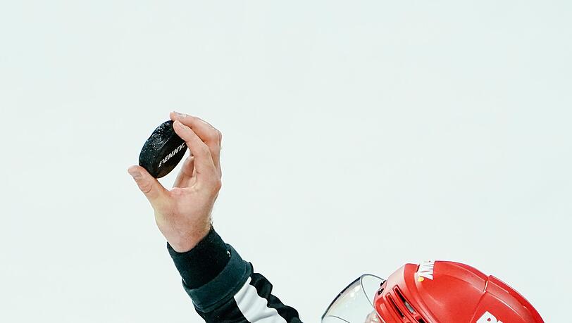 Ein Schiedsrichter hält den Puck in der Hand.