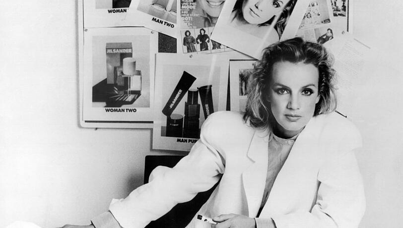 Jil Sander im Jahr 1983 in ihrem Büro, an dessen Wand Werbefotos ihrer Parfums hängen, die sie ab1979 in Zusammenarbeit mit dem Kosmetikhersteller Lancaster entwickelte. Jil Sander im Jahr 1983 in ihrem Büro, an dessen Wand Werbefotos ihrer Parfums hängen, die sie ab1979 in Zusammenarbeit mit dem Kosmetikhersteller Lancaster entwickelte.