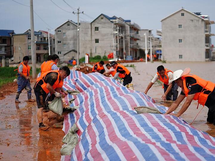 Rettungshelfer errichten einen provisorischen Deich gegen Überschwemmungen in einem Gebiet im Kreis Poyang in der ostchinesischen Provinz Jiangxi.