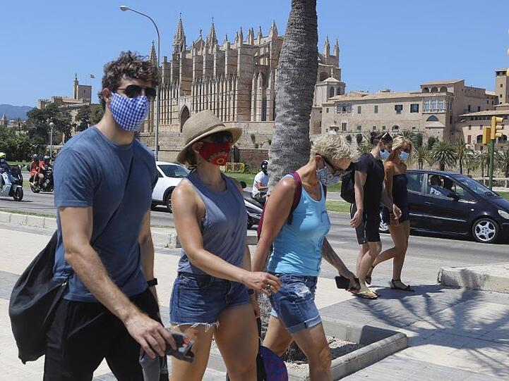 Junge Leute tragen einen Mund-Nasenschutz bei ihrem Gang durch Palma de Mallorca. Foto: Clara Margais/dpa/Archivbild