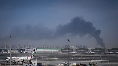 Blick auf den Flughafen von Dubai. Rauch steigt nach einem iranischen Angriff im Hintergrund auf. (Archivbild)