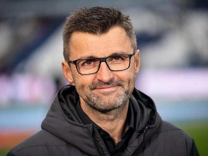 Michael Köllner steht in einem Stadion und lächelt in die Kamera. Foto: Swen Pförtner/Archiv