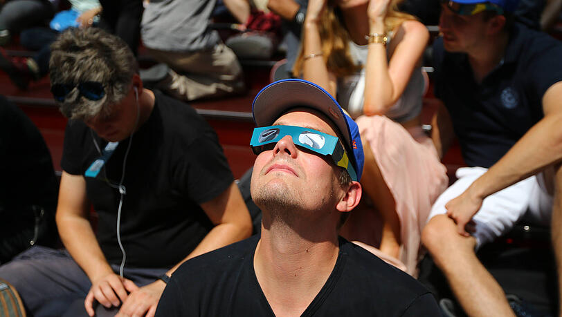 Ein Mann beobachtet mit einer speziellen Brille die Sonnenfinsternis. Solche Brillen stellt auch ein Unternehmen aus Mammendorf her.