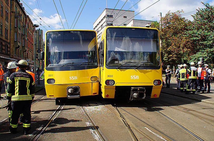 Einsatzkräfte der Feuerwehr stehen in Stuttgart neben den beiden entgleisten Stadtbahnen.