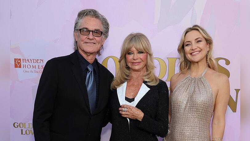 Kate Hudson strahlt bei einer Gala neben Goldie Hawn und Kurt Russell.