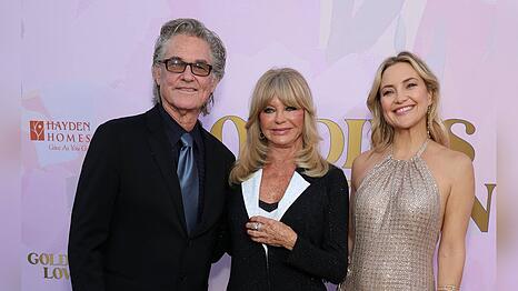 Kate Hudson strahlt bei einer Gala neben Goldie Hawn und Kurt Russell.