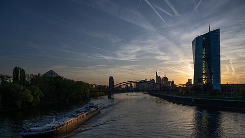 Ein Schiff fährt bei Sonnenuntergang an der EZB in Frankfurt vorbei.