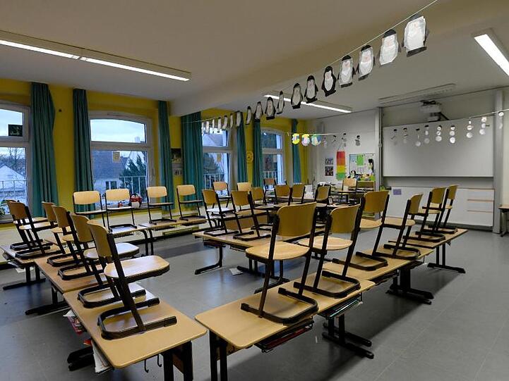 Stühle stehen in einem Klassenzimmer in einer Grundschule auf den Tischen. Foto: Caroline Seidel/dpa/Archivbild