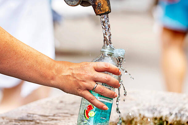 Eine Frau f&uuml;llt Wasserflasche mit frischem Trinkwasser am Marienplatz.