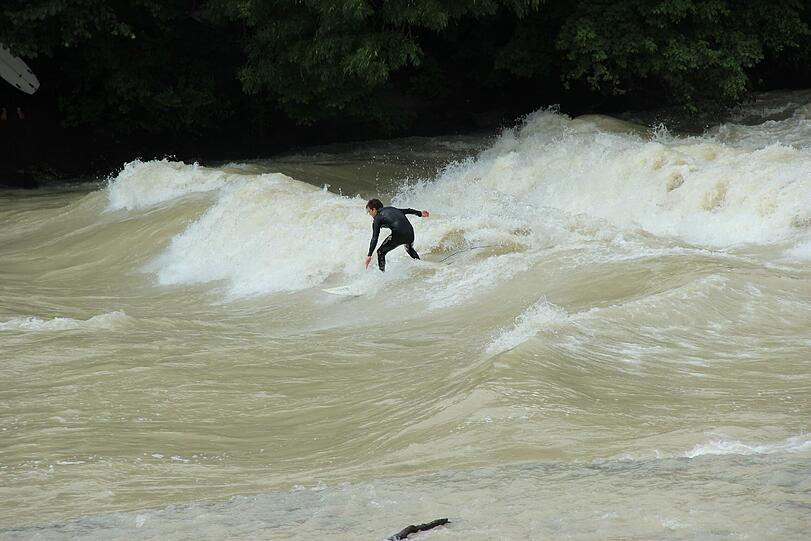 Hochwasser für die einen, perfekte Wellen für die anderen. Waghalsig tummeln sich Sportler in der Isar.