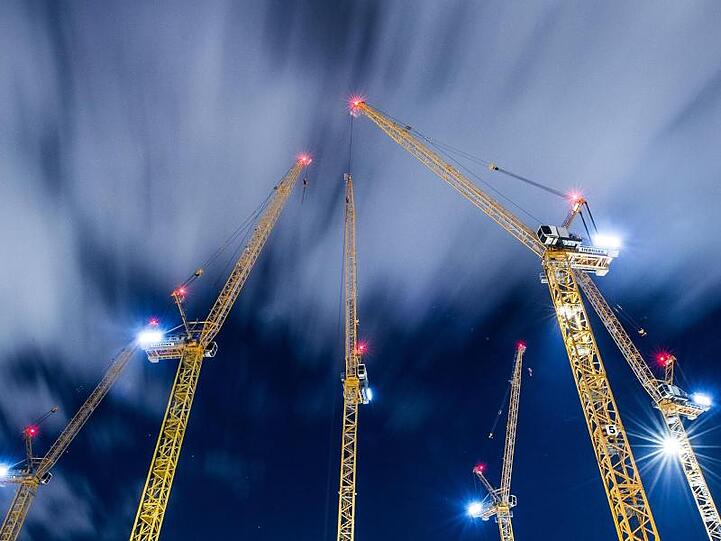 Wolken ziehen über Baukräne auf einer Großbaustelle hinweg. Foto: Silas Stein/dpa/Archivbild