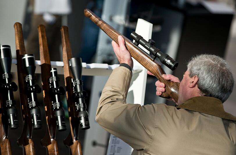 Ein Messebesucher blickt am 07.03.2014 in Nürnberg auf der Jagd- und Sportwaffenmesse IWA & OutdoorClassics durch ein Zielfernrohr am Stand des deutschen Herstellers Minox.