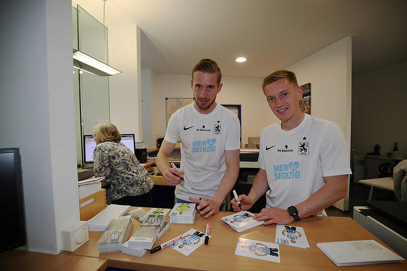 Vor dem Arbeitsbeginn an der Kasse signieren die 1860-Spieler Marco Hiller (l.) und Fabian Greilinger schnell noch ein paar Autogrammkarten.