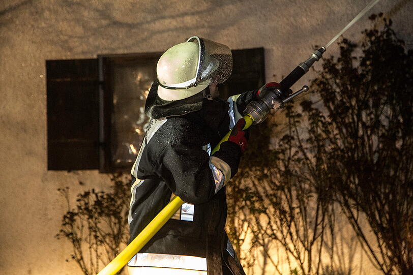 Die Feuerwehr bekämpft die Flammen mit Wasserrohren am Boden.