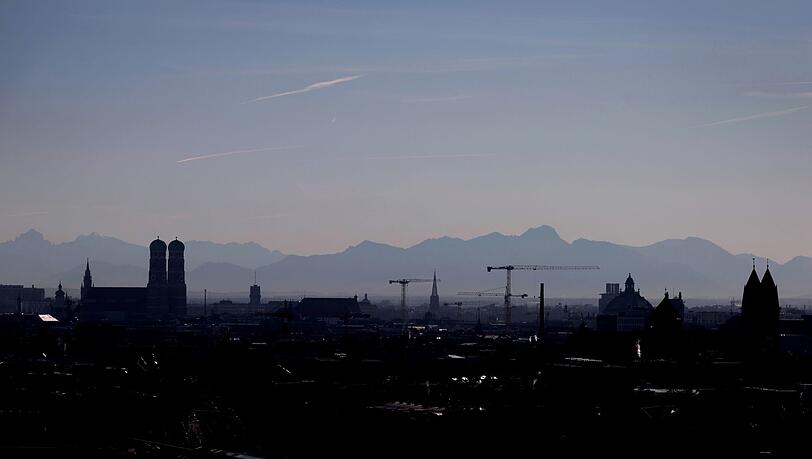 Die Umrisse der Frauenkirche (l) und von Baukränen zeichnen sich vor dem Panorama der Alpen ab.