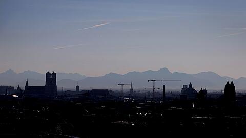 Die Umrisse der Frauenkirche (l) und von Baukränen zeichnen sich vor dem Panorama der Alpen ab.