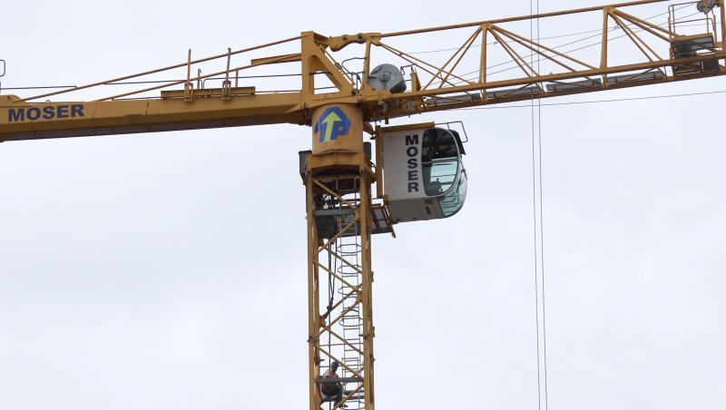 Ein Bauarbeiter sitzt auf einem Baukran. Foto: Alexander Auer/dpa