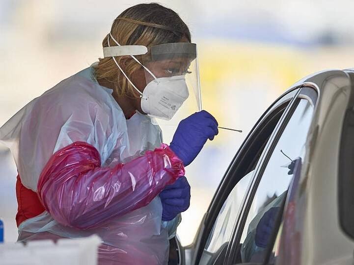 Eine Krankenschwester in Schutzanzug nimmt in Omaha einen Nasenabstrich von einem Patienten für einen Corona-Schnelltest.