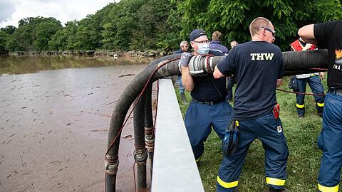 Nordrhein-Westfalen, Euskirchen: Helfer des Technischen Hilfswerks (THW) lassen Schläuche in die Steinbachtalsperre hinab, um das Wasser abzupumpen. Der Damm der Talsperre droht einstürzen.