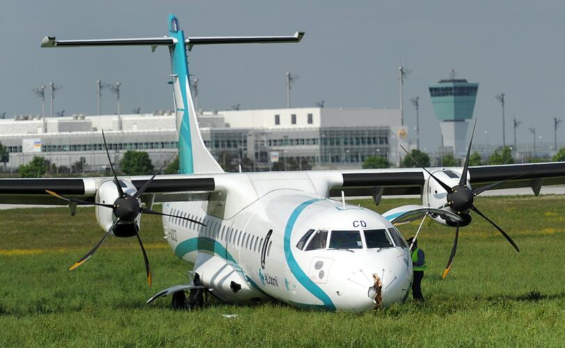 Mitarbeiter des Flughafens in München betrachten die Maschine der italienischen Fluggesellschaft, die am Donnerstag auf dem Münchner Flughafen notlanden musste. Das Flugzeug mit 62 Menschen an Bord hatte kurz nach dem Start in Richtung Venedig umdrehen müssen, weil sich Rauch in der Kabine entwickelt hatte. Bei der Landung wurden fünf Personen leicht verletzt, die Maschine kam neben der Landebahn zum Stehen.