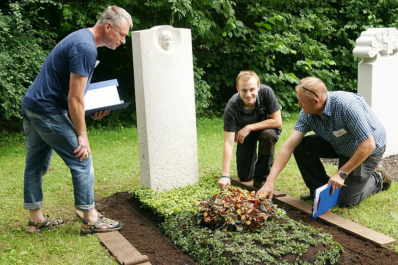 Es ist vollbracht: Robert Schwarz zeigt den Prüfern sein Abschlussgrab am Westfriedhof. Justus Hegemann (l.) wirft einen kritischen Blick auf die Arbeit, Paul Kudett tastet die Erde ab.