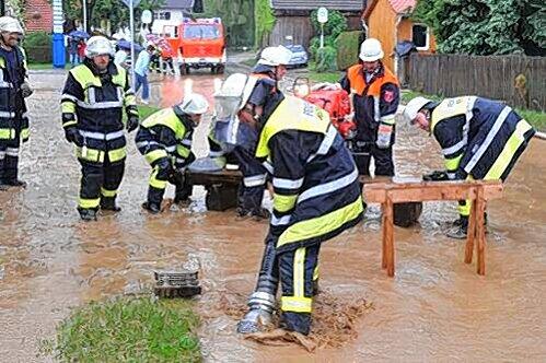 Ein See aus Wasser und Schlamm: Feuerwehrmänner beim Schöpfen und Abpumpen im Ortskern von Purching.