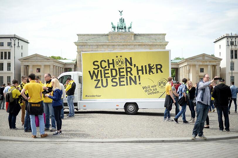Ein BVB-Werbeauto steht in Berlin vor dem Brandenburger Tor und präsentiert das Finalmotto des BVB: "Schön, wieder da zu sein!"