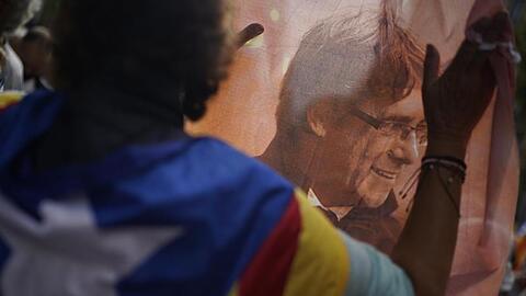 Ein Mann hält ein bedrucktes Tuch mit dem Bild des ehemaligen katalanischen Regierungschefs Puigdemont während eines Protests vor dem italienischen Konsulat in Barcelona.