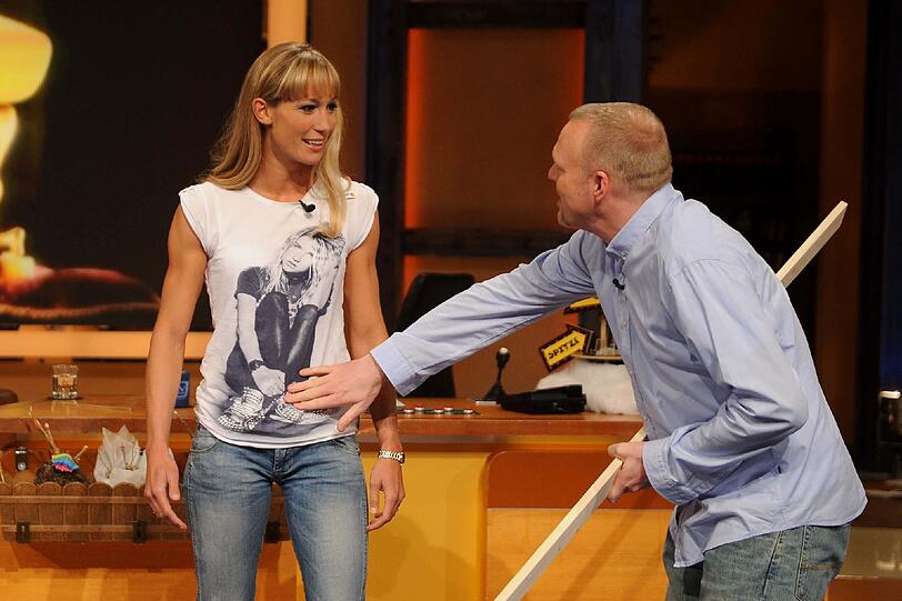 Stefan Raab begutachtet sein Ziel: Er will die Latte an Christine Theiss' Bauch zerschlagen.