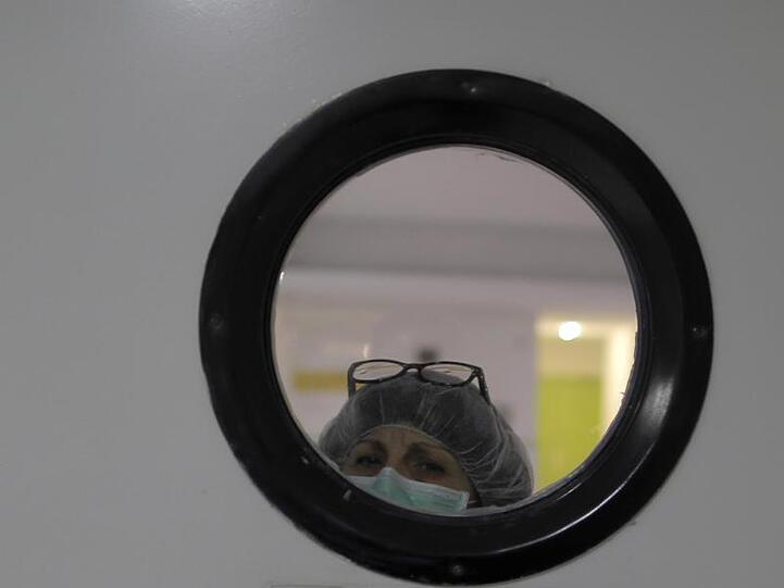 Eine Mitarbeiterin mit Mundschutz schaut aus einem Fenster in einem Pflegeheim in Madrid.