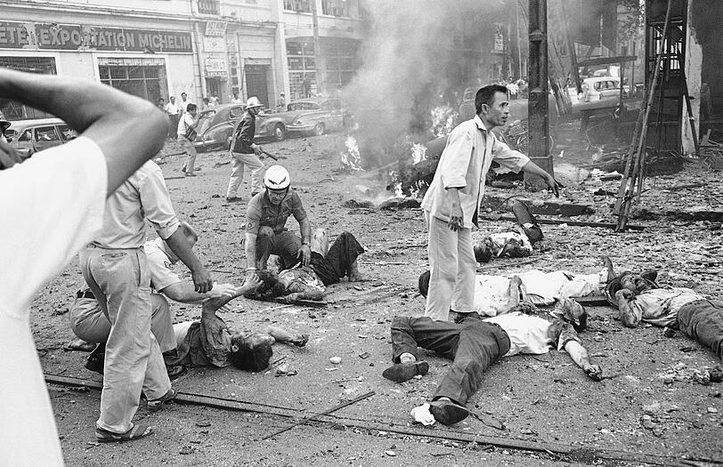 Verletzte Vietnamesen, die nach einer Bombenexplosion außerhalb der US-amerikanischen Botschaft in Saigon auf der Straße liegen, erhalten Hilfe.