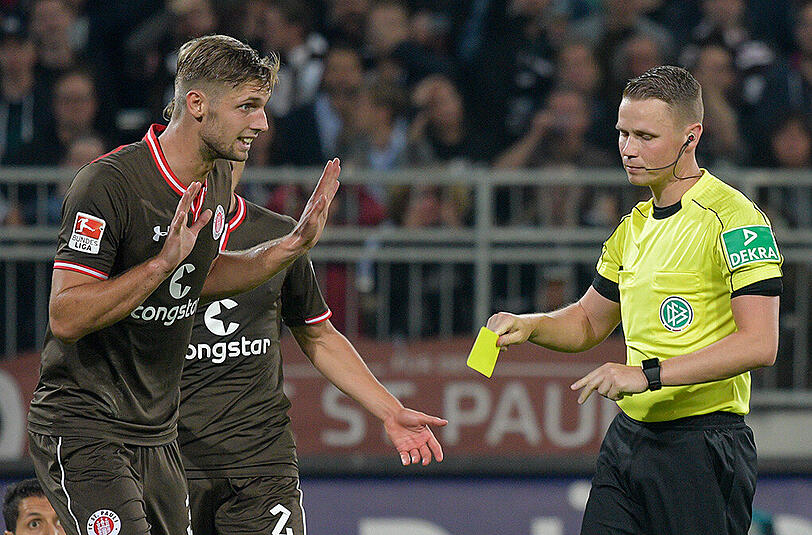 Schiedsrichter Robert Kampka (rechts) zeigt St. Paulis Lasse Sobiech im Spiel gegen dem TSV 1860 die gelbe Karte.