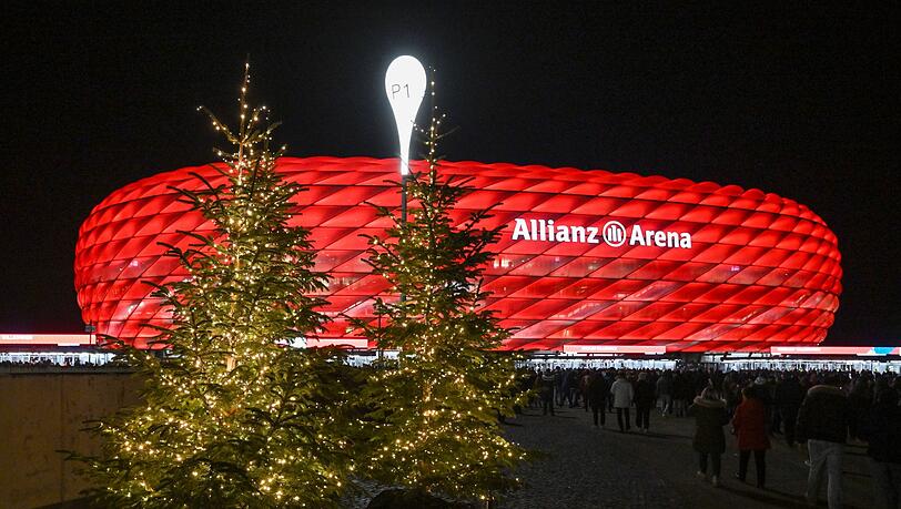Beleuchtete Weihnachtsbäume stehen vor der Partie im Zugang zum Stadion.