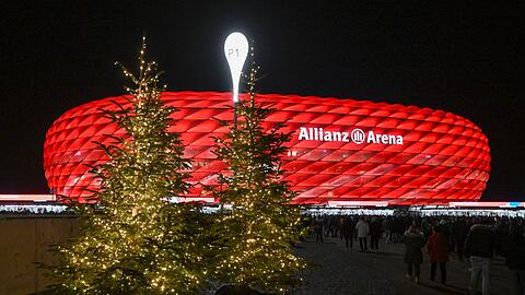Beleuchtete Weihnachtsbäume stehen vor der Partie im Zugang zum Stadion.