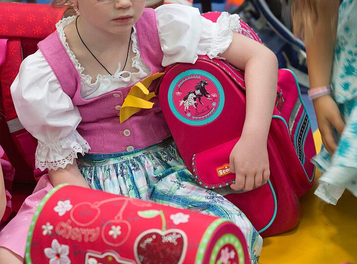 Ein Mädchen mit neuem Schulranzen wartet auf den Unterrichtsbeginn.