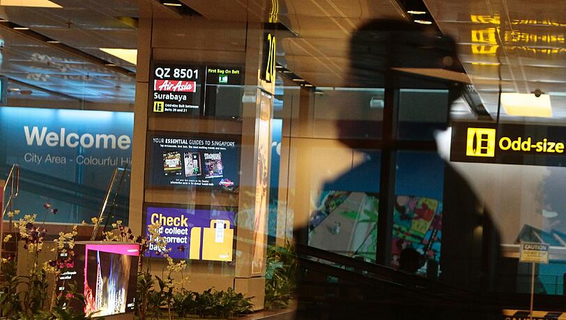 Am Gepäckband in Singapur wird Flug QZ 8501 aus Surabaya angekündigt Am Gepäckband in Singapur wird Flug QZ 8501 aus Surabaya angekündigt
