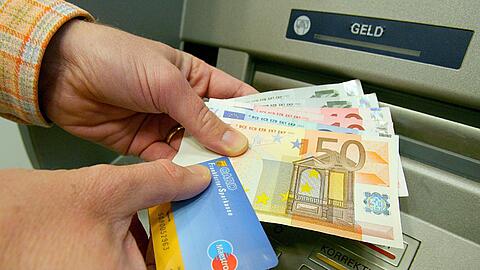 Ein Kunde hebt Geld mit seiner Girokarte ab. Manchmal lohnt es sich, für sein Girokonto ein bisschen Geld abzuzwicken und dafür andere Vorteile zu kassieren.