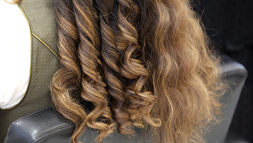 Die unteren Haare, die später offen bleiben werden, mit einem Lockenstab oder einem Glätteisen locken.