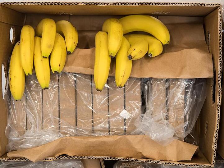 Päckchen zu je einem Kilo mit Kokain und Bananen liegen in einer Kiste. Foto: Peter Kneffel/dpa/Archivbild