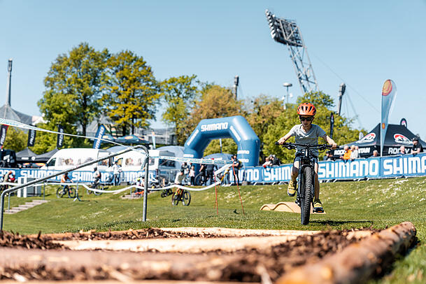 Ein Kind flitzt mit dem E-Mountainbike über holprigen Boden.