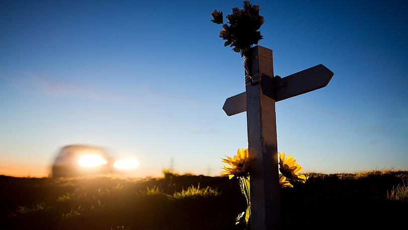 Ein Kreuz und Blumen zur Erinnerung an einen Verkehrstoten stehen in der Abenddämmerung einer Landstraße bei Sehnde. Ein Kreuz und Blumen zur Erinnerung an einen Verkehrstoten stehen in der Abenddämmerung einer Landstraße bei Sehnde.