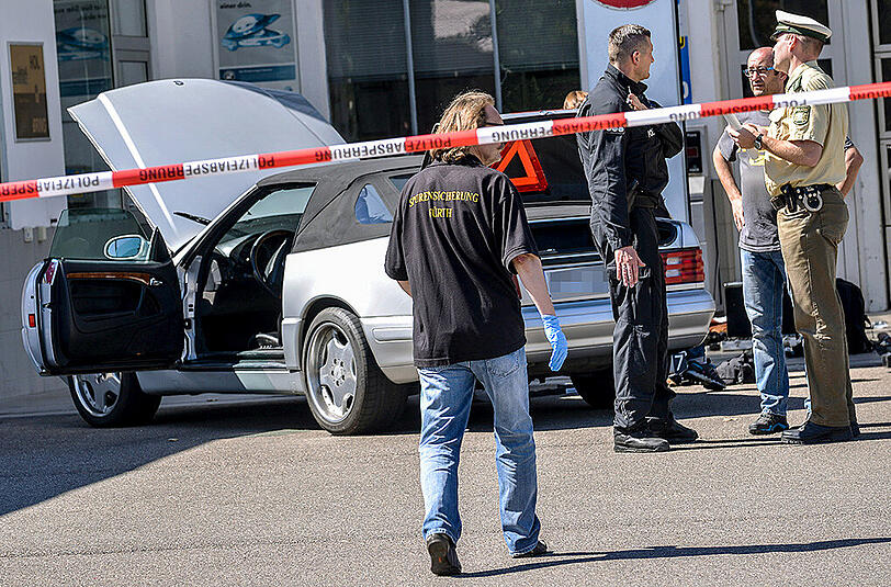 Beamte der Polizei und Spurensicherung stehen an einer Tankstelle vor dem Auto des mutmaßlichen Amokläufers. (Archivbild)
