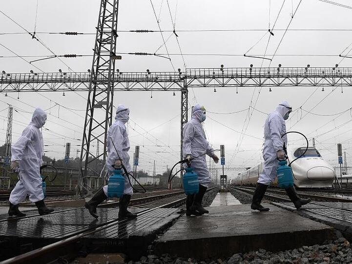 Mitarbeiter der Bahn sind in der chinesischen Stadt Guangxi auf dem Weg zu Zügen, um diese zu desinfizieren.