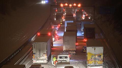 Autos und Lastwagen stecken am frühen Morgen bei Schneefall auf der verschneiten Autobahn 4 bei Dresden fest.
