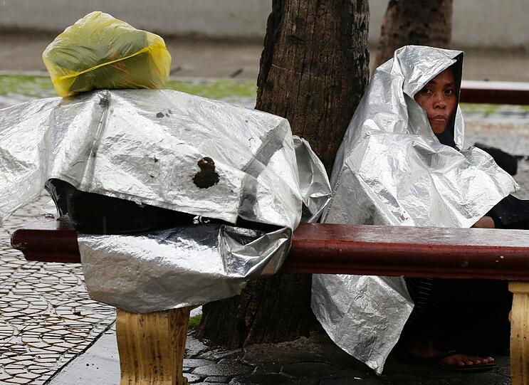 Philippinerin schützt Ihr Gepäck und sich mit Plastikfolien vor dem Taifun Haiyan.