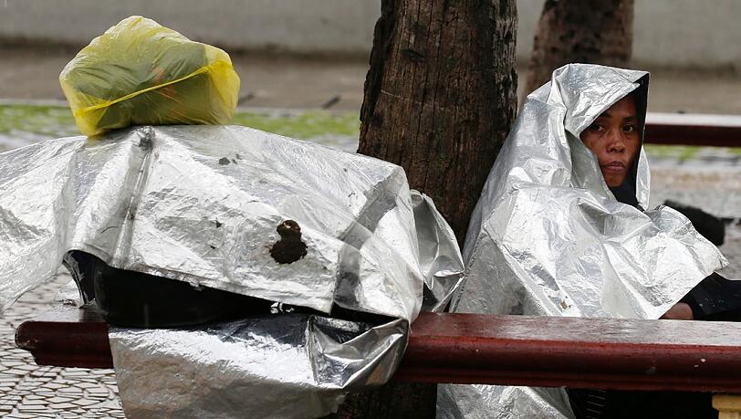 Philippinerin schützt Ihr Gepäck und sich mit Plastikfolien vor dem Taifun Haiyan.