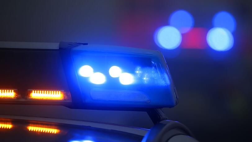 Ein Polizeiauto mit eingeschaltetem Blaulicht steht an einer Unfallstelle.